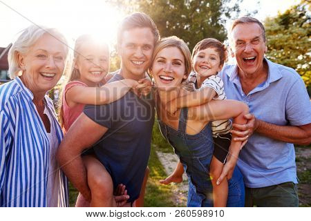 Portrait Of Smiling Multi Generation Family Outdoors In Summer Park Against Flaring Sun