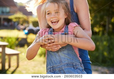 Close Up Of Mother Playing Game And Swinging Daughter Around In Garden Of Summer Pub