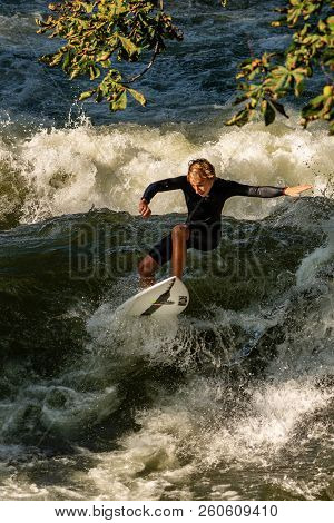 Munich, Germany - Sept 8, 2018: A Man Surfing In The Waves Of The Eisbach River In Downtown Of Munic