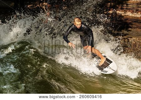 Munich, Germany - Sept 8, 2018: A Man Surfing In The Waves Of The Eisbach River In Downtown Of Munic