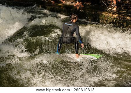 Munich, Germany - Sept 8, 2018: A Man Surfing In The Waves Of The Eisbach River In Downtown Of Munic