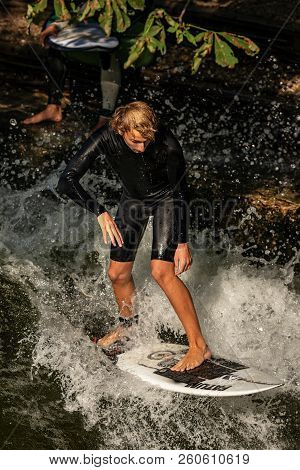 Munich, Germany - Sept 8, 2018: A Man Surfing In The Waves Of The Eisbach River In Downtown Of Munic