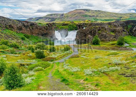 View Of Hjalparfoss Waterfalls And The Flowers Field In The Thjorsardalur Valley At The South Of Ice