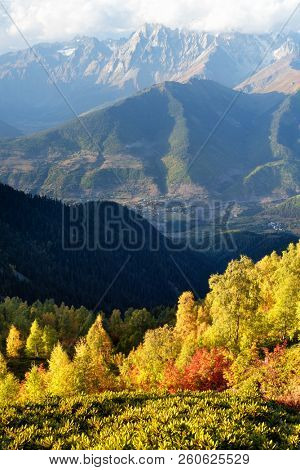 Autumn in Zemo Svaneti, Georgia. Ushba peak in clouds. View from Mount Mkheer on Main Caucasian ridge. Landscape with birch forest on hillside