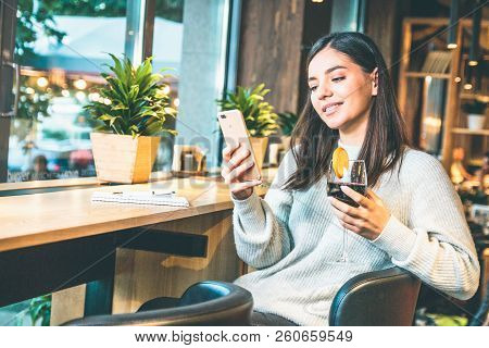 Christmas Concept - Happy Young Woman With Glass Of Wine Or Glintwine Checking The Phone