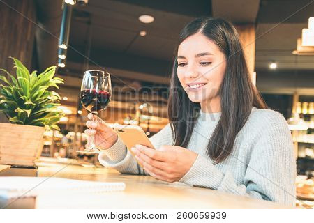Close Up Of A Happy Young Woman With Glass Of Wine Or Glintwine Checking The Phone