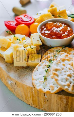Cheese Board With Tomatoes, Jam, Baguette, Bread Sticks And Crackers