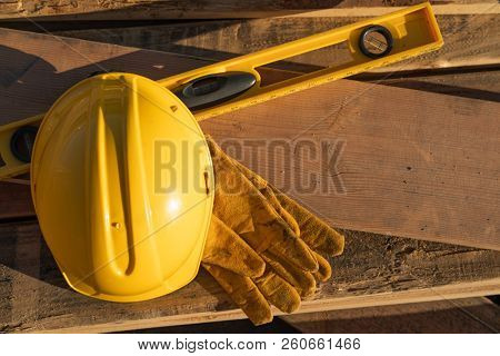 Abstract of Constrcution Hard Hat, Gloves and Level Resting on Wood Planks.