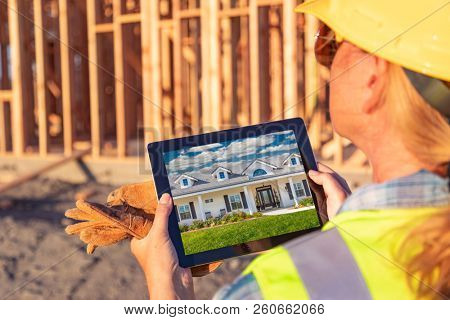 Female Construciton Worker Reviewing House Photo on Computer Pad at Construciton Site.