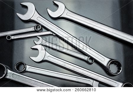 Metal Flat Wrenches Lying On A Black, Shiny Table, Flat View From Above.