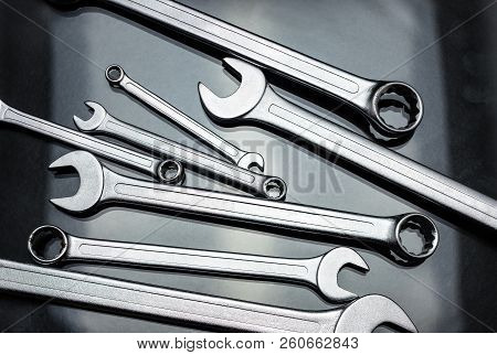 Metal Flat Wrenches Lying On A Black, Shiny Table, Flat View From Above.