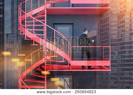 Young Businessman With Smartphone Standing On Black Building Emergency Stairs. Having A Plan B Conce