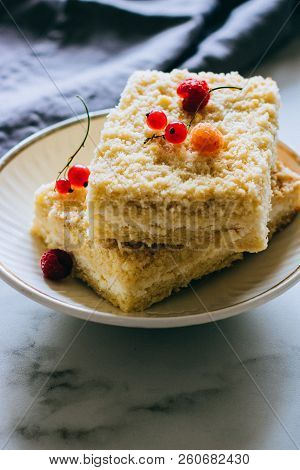 Pieces Of Cottage Cheese Cake With A Crumble Decorated With Raspberries And Red Currants On A White
