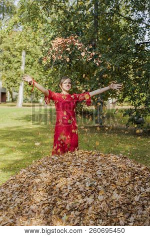 Young Woman In Red Dress. Toss The Autumn Leaves Upward.