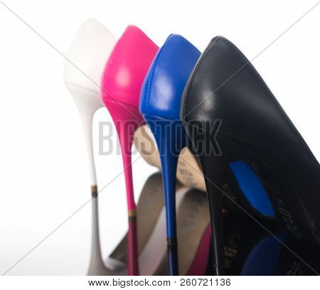 Black, Blue Pink And White High Heels Pointed Woman Shoes On The Back And Heels On Reflective Floor.