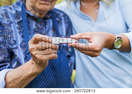 Close Up Picture Of Young Woman Holding Pregnancy Test With Grandmother. Great-grandchild On The Way