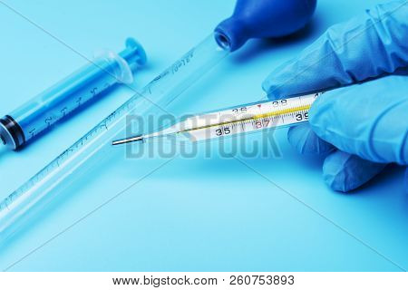 Hand In Glove Holding A Thermometer Of Public Health And Medicine.
