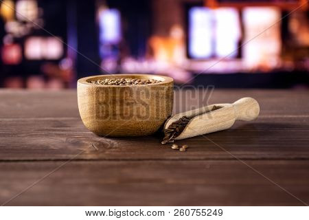 Lot Of Whole Fresh Brown Flaxseeds In A Scoop With Wooden Bowl With Restaurant In Background