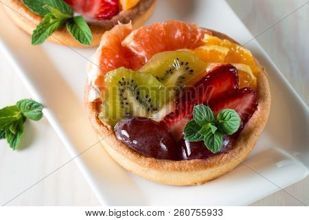 Fresh Fruit And Berry Tart Dessert With Toss Sugar On Wooden Background. Delicious Sweet Cake With R