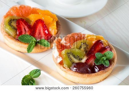 Fresh Fruit And Berry Tart Dessert With Toss Sugar On Wooden Background. Delicious Sweet Cake With R