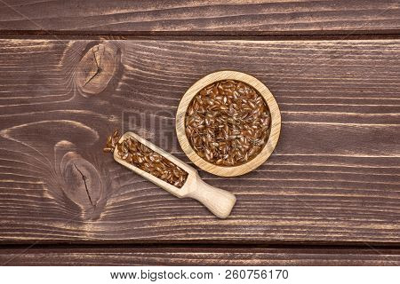 Lot Of Whole Fresh Brown Flaxseeds In A Scoop With Wooden Bowl Flatlay On Brown Wood