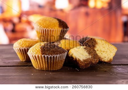 Group Of Four Whole Two Halves Of Fresh Baked Marble Muffin With Rustic Wood Kitchen In Background