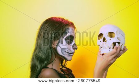 Halloween, Girl With Make-up Skeleton On Half Face, Dressed As Witch, Posing On Bright Yellow Backgr