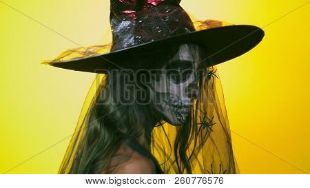 Halloween, Girl With Make-up Skeleton On Half Face, Dressed As Witch, Posing On Bright Yellow Backgr