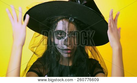 Halloween, Girl With Make-up Skeleton On Half Face, Dressed As Witch, Posing On Bright Yellow Backgr
