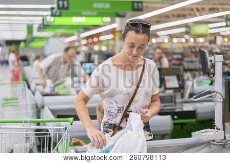 A Middle-aged Woman At The Checkout In The Supermarket. The Woman Counts On The Checkout In The Supe