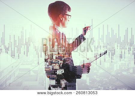 Handsome European Busnessman Holding Document And Drawing Forex Chart On Abstract City Background. O