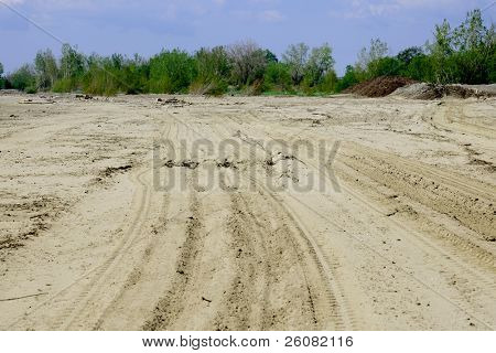 Tire tracks mark the sand on a beach.