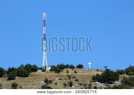 Tall Cell Phone Red And White Antenna Tower Next To Small Building Situated On Top Of The Hill With 