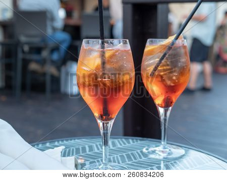 Two Full Spritz Drinks Sitting On Outdoor Glass Table In Restaurant