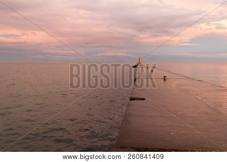 A Lighthouse Pier On Lake Michigan At Sunset With Pink Clouds Reflected In The Water.  Sheboygan, Wi