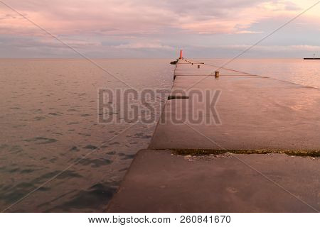 A Lighthouse Pier On Lake Michigan At Sunset With Pink Clouds Reflected In The Water.  Sheboygan, Wi