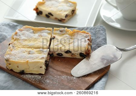 Homemade cheesecake with raisins topped with powdered sugar on a cutting board
