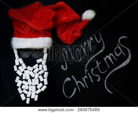 Chalked Santa Claus With A Real Red Cap And A Marshmallow Beard On A Chalkboard And A Chalk Inscript