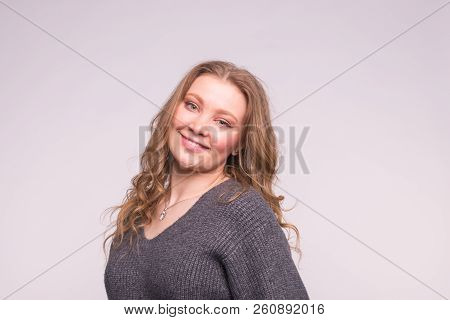 Portrait Of Fashionable Young Blonde Woman With Curly Hair In Grey Cardigan On White Background
