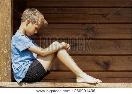 Sad Unhappy Lonely Boy Sitting In Wooden Teracce Outdoors