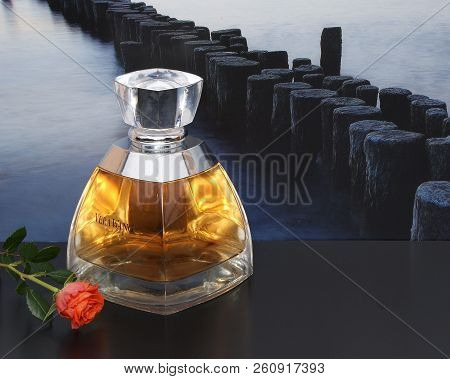 Vera Wang, Fragrance For Ladies, Large Perfume Bottle In Front Of The Picture Of A Groyne In The Sea