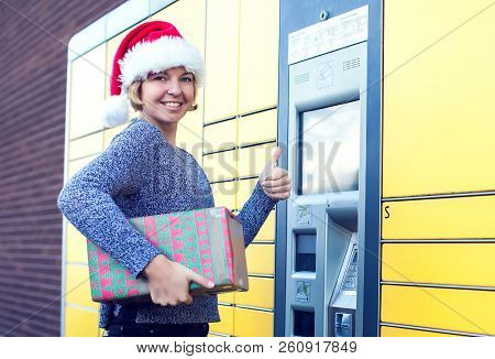 Woman With Santa Christmas Hat Client Using Automated Self Service Post Terminal Machine Or Locker T