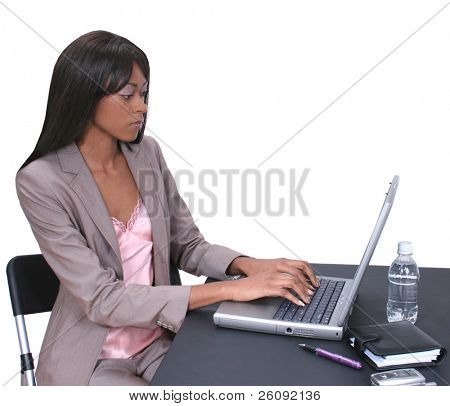 Smuk African American kvinde i business påklædning arbejder på en bærbar computer.