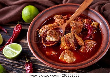 Hearty Red Chile And Pork Stew Or Carne Adobada In A Clay Bowl With Spoon On An Old  Wooden Table Wi