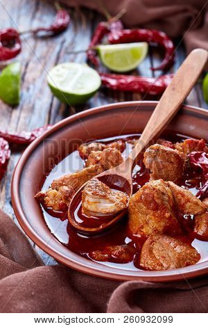 Carne Adobada Or Hearty Red Chile And Pork Stew In A Clay Bowl With Spoon On An Old Wooden Table Wit