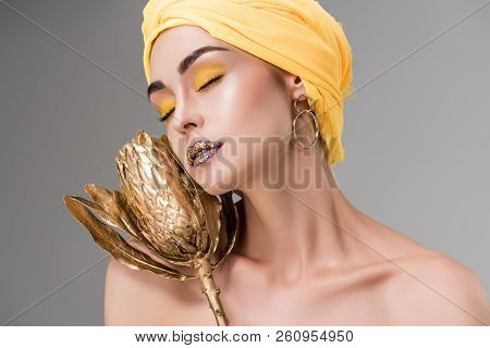 Sensual Naked Girl In Yellow Turban Holding Golden Protea Flower Isolated On Grey