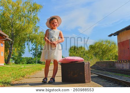 Happy Girl On A Railway Station, Waiting For The Train With Vintage Suitcase. Traveling, Holiday And