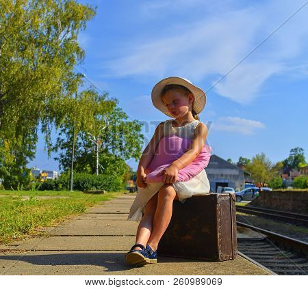 Cute Girl Holding Plush Toy On A Railway Station, Waiting For The Train With Vintage Suitcase. Trave