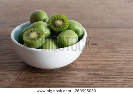 Hardy Kiwi Fruits Or Kiwi Berry Actinidia Arguta In Ceramic Bowl On Wooden Kitchen Table