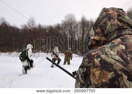 Group Of Hunters In Winter Forest With Carbines And Shotgun At Dawn